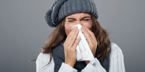 woman in winter clothes sneezing
